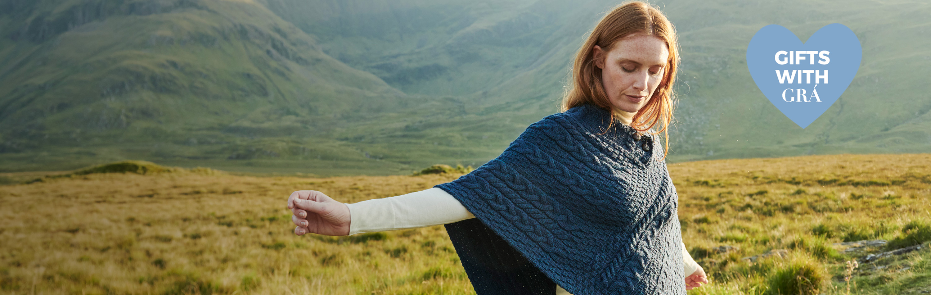 Red haired woman enjoying a rural irish setting wearing Aran knitwear